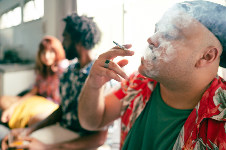 Man smoking marijuana while friends chat
